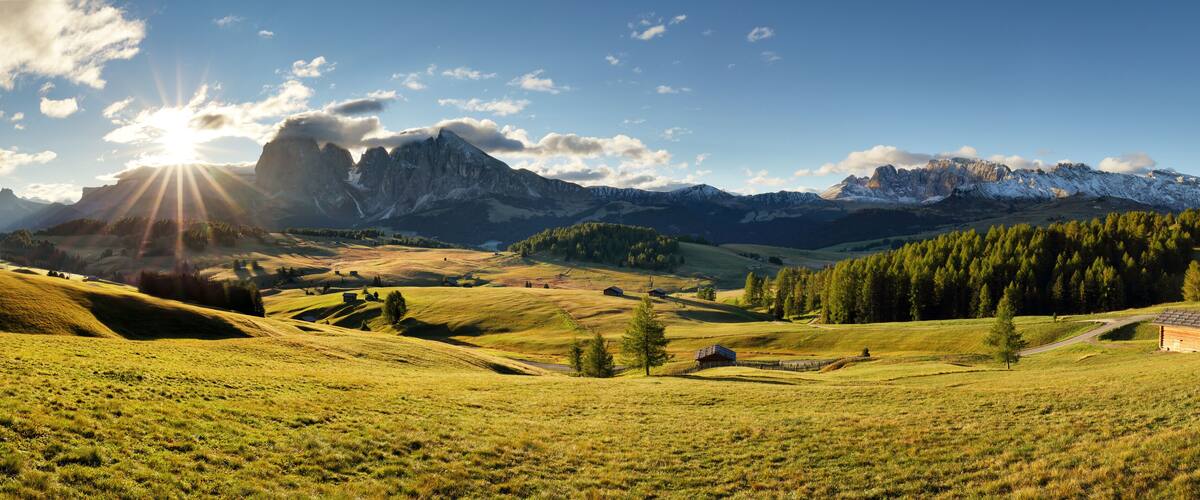 A mountainous landscape with a small cabin, rolling hills, and a clear sky.