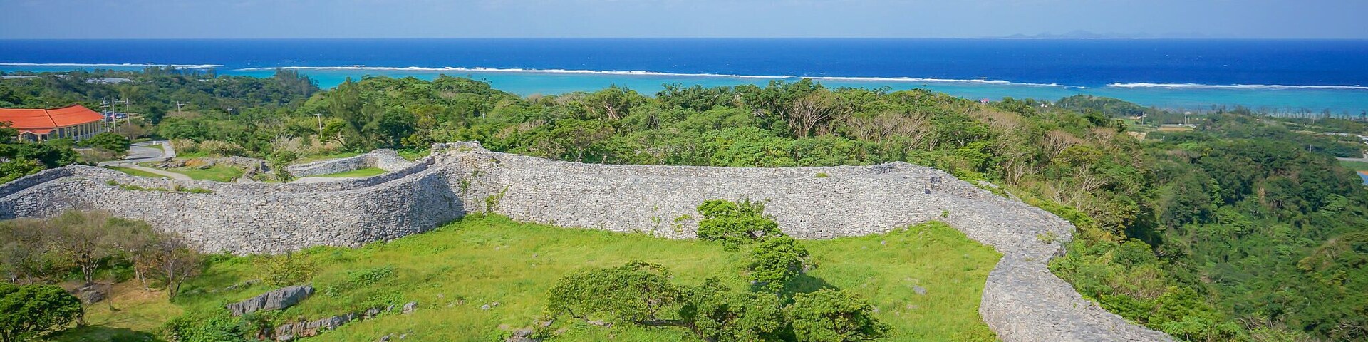 Una fortificación de piedra rodeada de exuberante vegetación y vistas al mar.