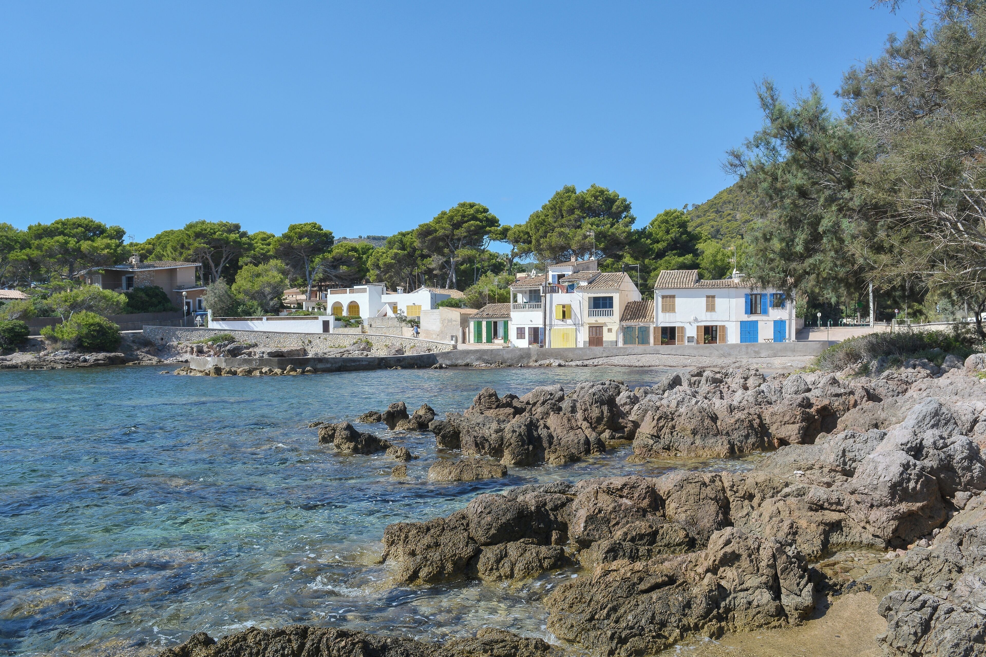 A coastal village with clear blue waters, rocky shore, and colorful houses.