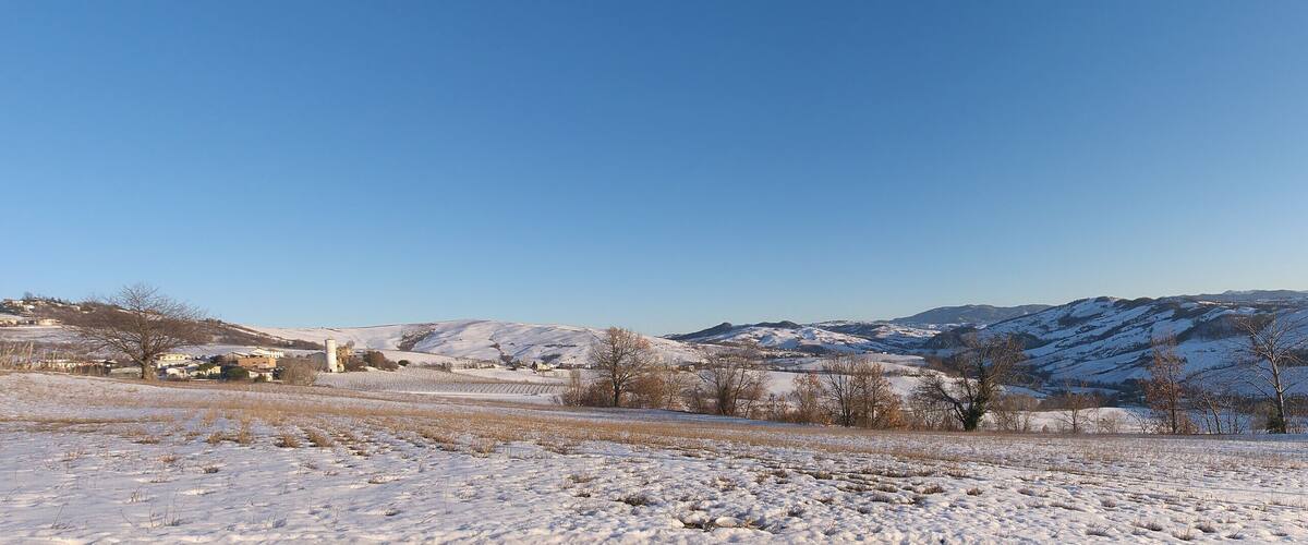 A snow-covered landscape with mountains in the background and a clear blue sky.