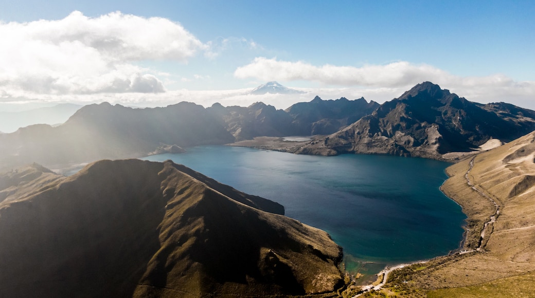 Un paysage montagneux avec un grand lac, entouré d’un terrain accidenté et dominé par des sommets enneigés au loin.