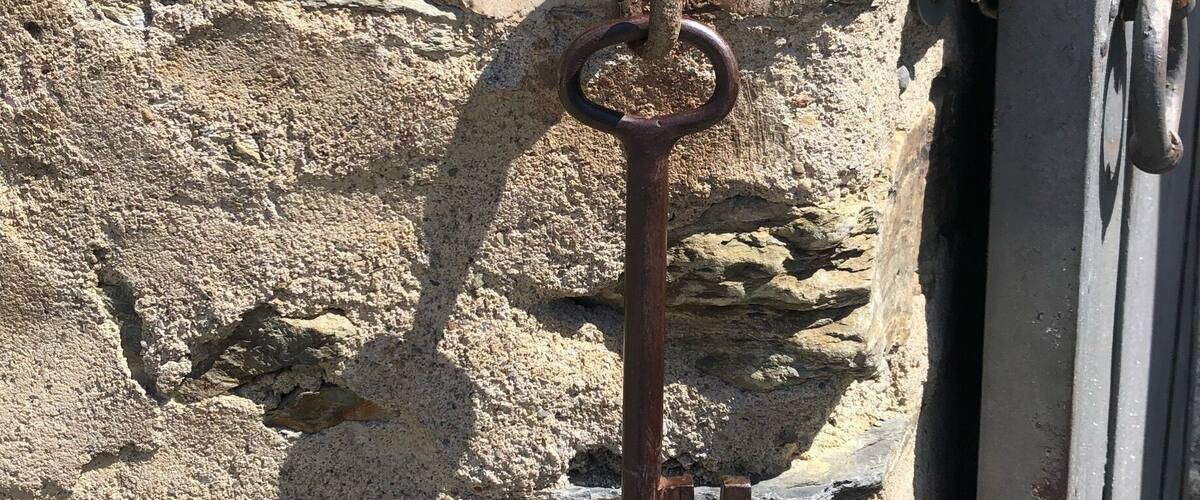 An old rusty key attached to a stone wall.