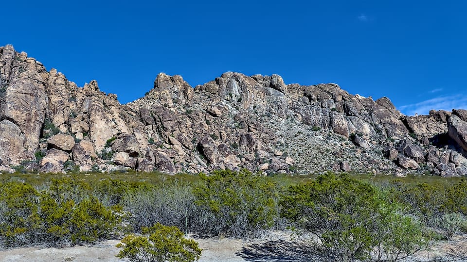 Eine zerklüftete Bergkette mit spärlicher Vegetation im Vordergrund.