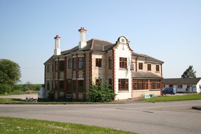 A two-story brick building with a large window and a chimney.