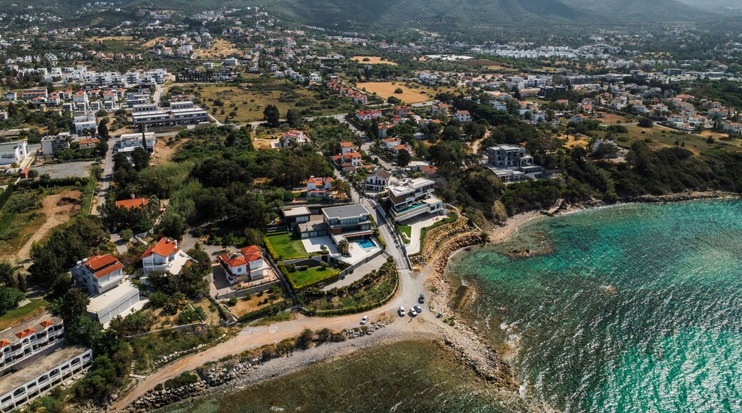 Aerial view of beautiful sandy beach and coastal village with homes and mountains, Agios Georgios Keryneias, Kyrenia, Turkish Republic of Northern Cyprus.