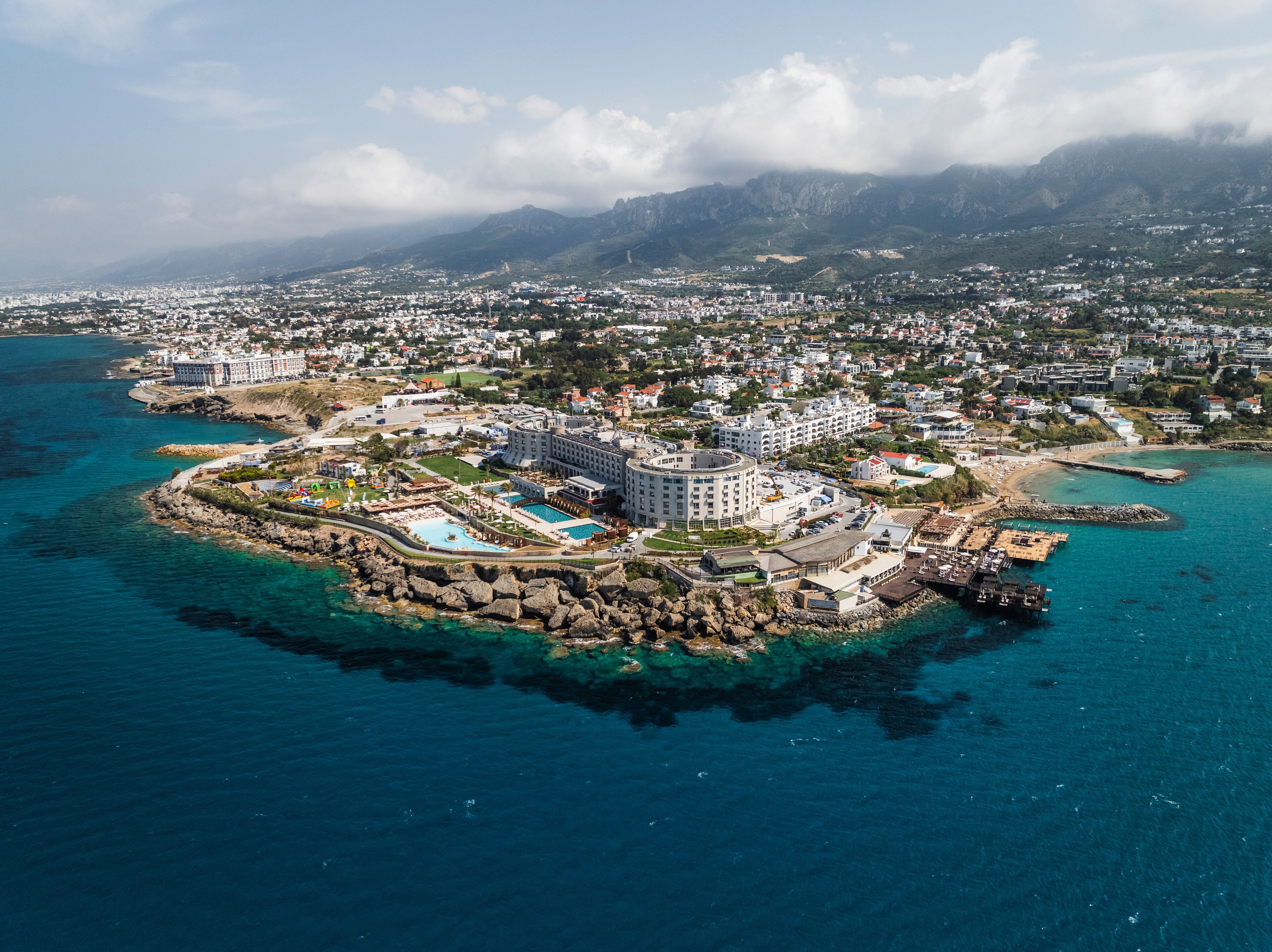 Aerial view of beautiful coastline with clear water, buildings, and mountains, Agios Georgios Keryneias, Kyrenia, Turkish Republic of Northern Cyprus.