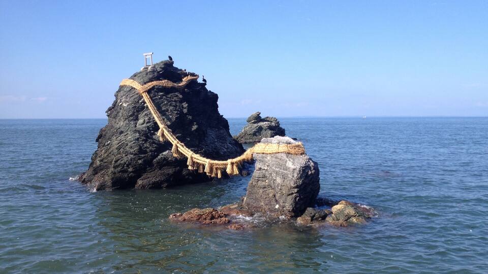 A rocky island with a rope bridge and a wooden structure on top.