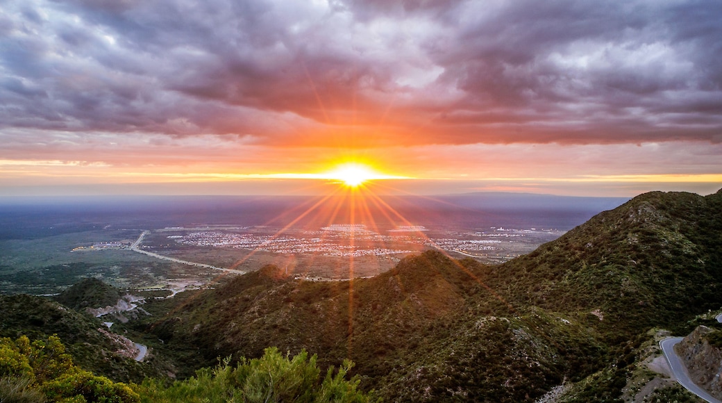 A sunset over a coastal city with a mountainous backdrop.