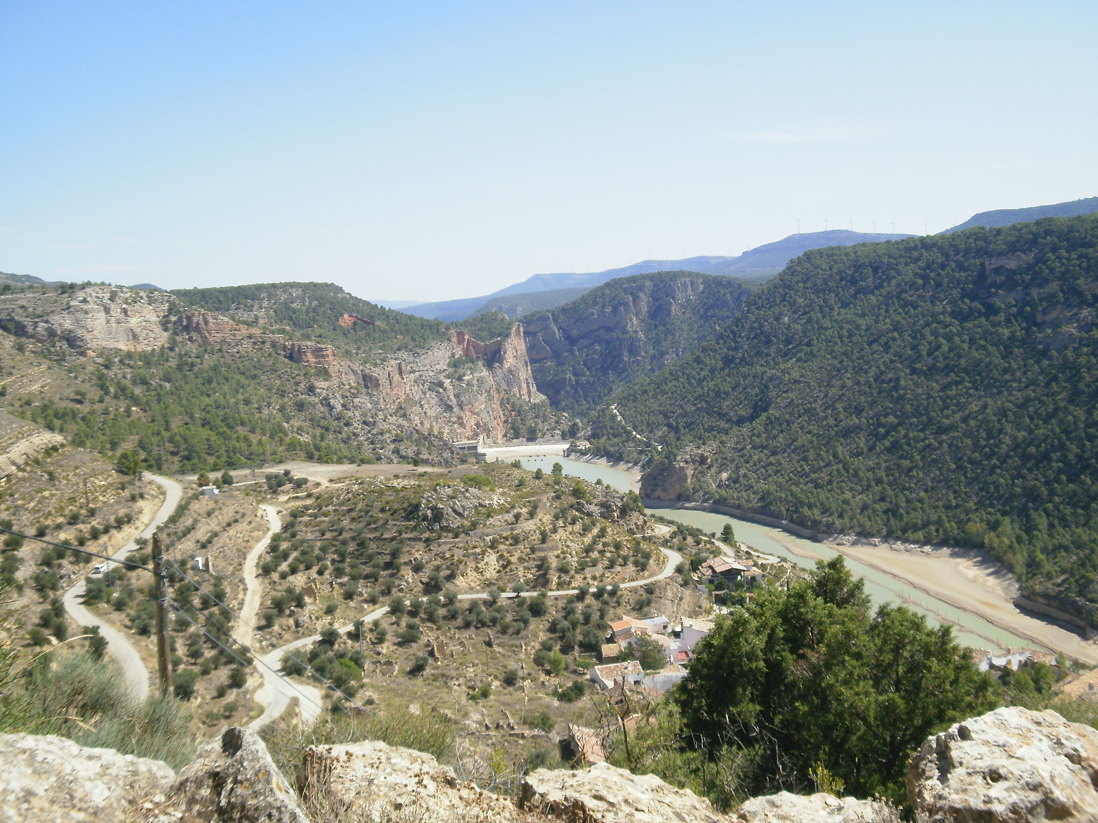 A mountainous landscape with a winding river, rocky terrain, and scattered buildings.