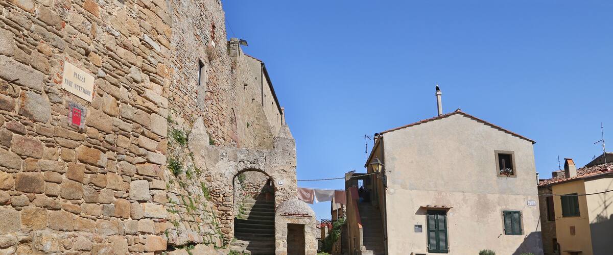 A stone building with a sign, a staircase, and a cobblestone street.