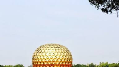 A large golden sphere with a patterned surface, surrounded by red pyramidal structures.