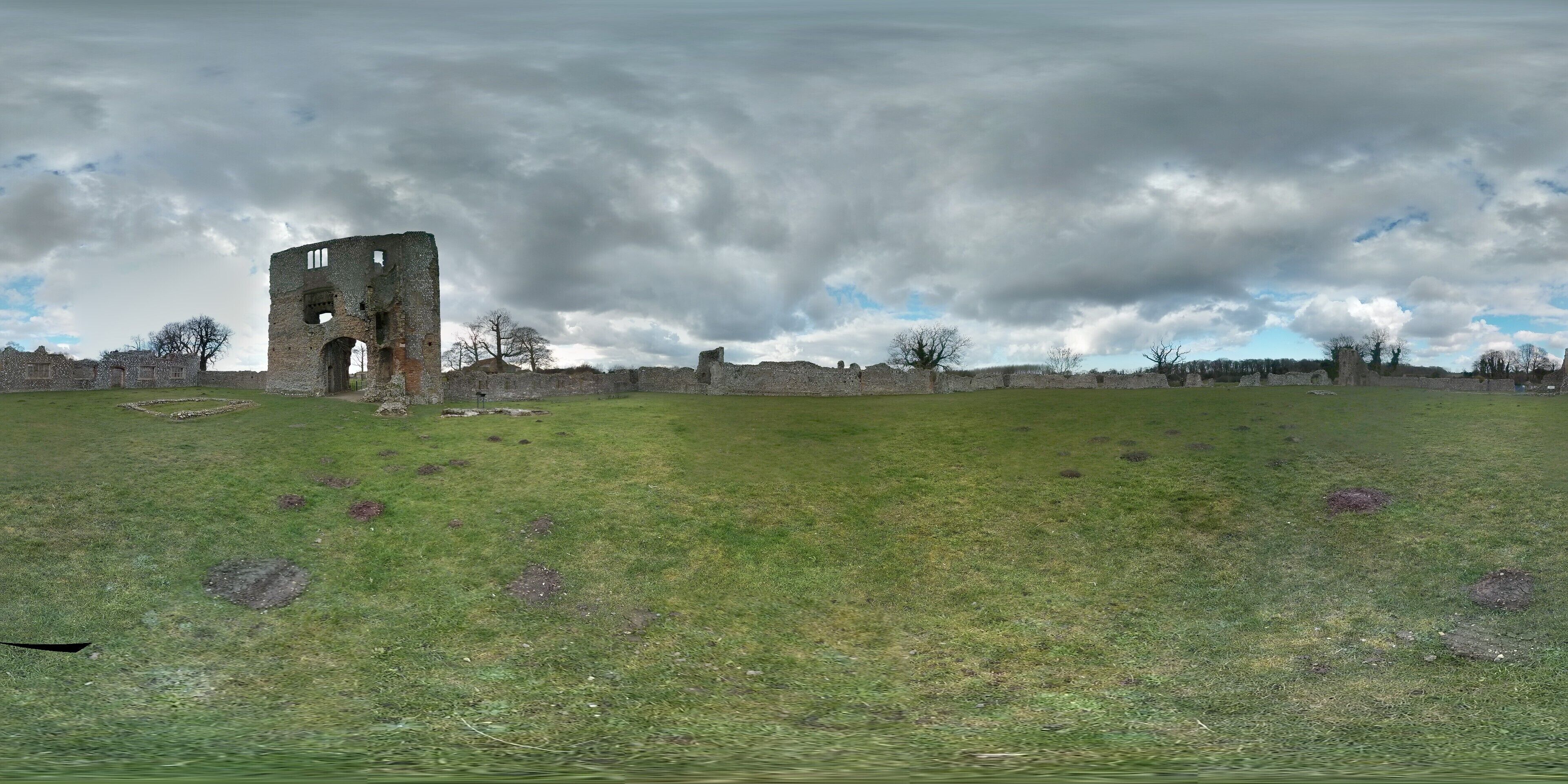 A grassy field with a stone tower ruin and scattered stone walls.