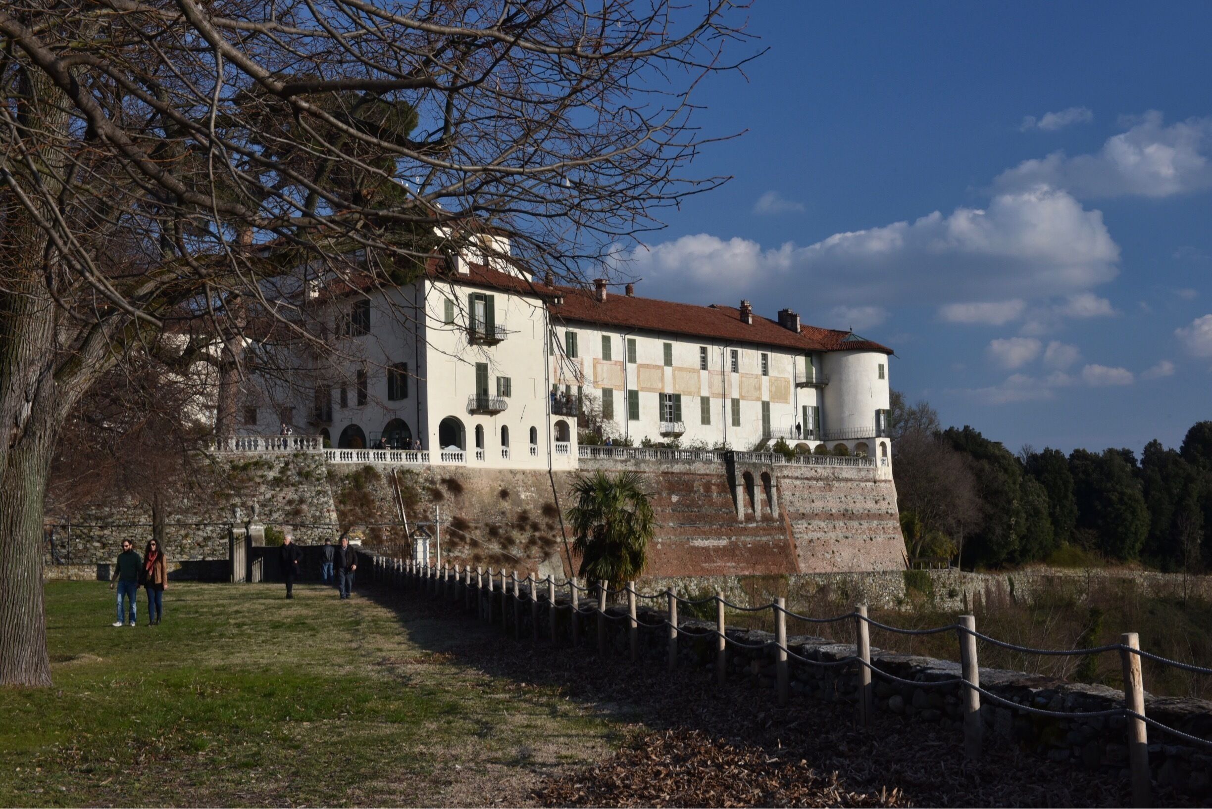 A historic building with a red-tiled roof, arched windows, and a stone wall.