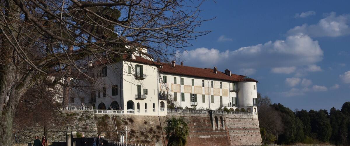 A historic building with a red-tiled roof, arched windows, and a stone wall.