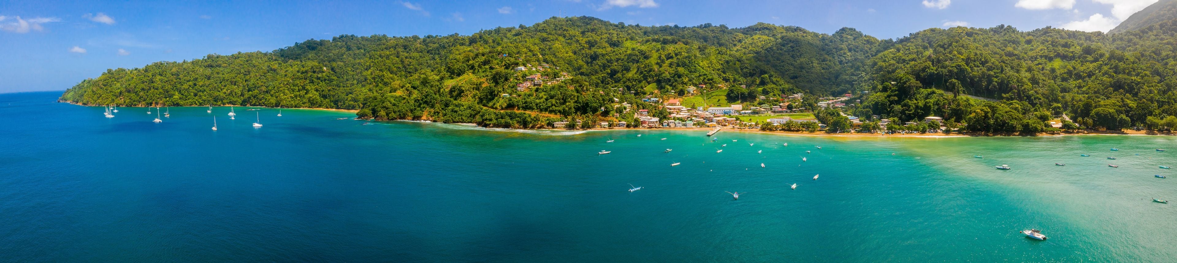 Un paisaje costero con una isla boscosa, aguas turquesas cristalinas y numerosos barcos.