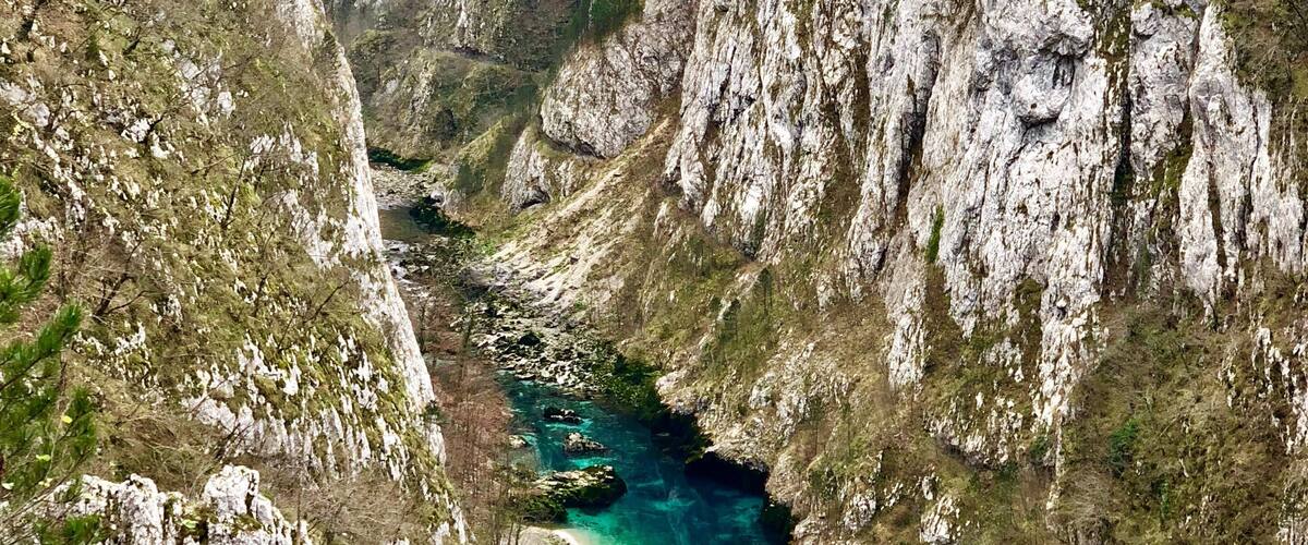 A bridge over a river in a canyon with rocky cliffs.