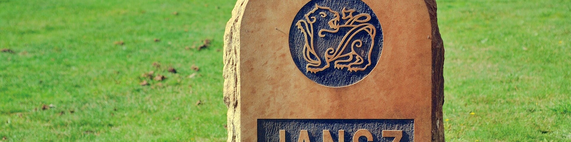 A stone monument with the inscription "JANSZ" and a decorative emblem.
