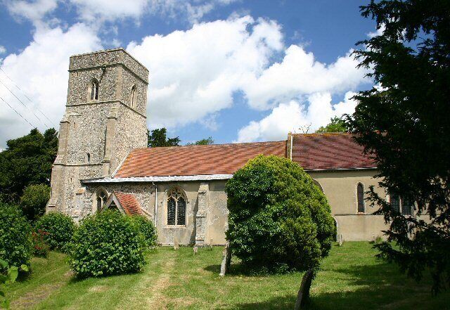 A church with a tower and a red-tiled roof, surrounded by greenery.