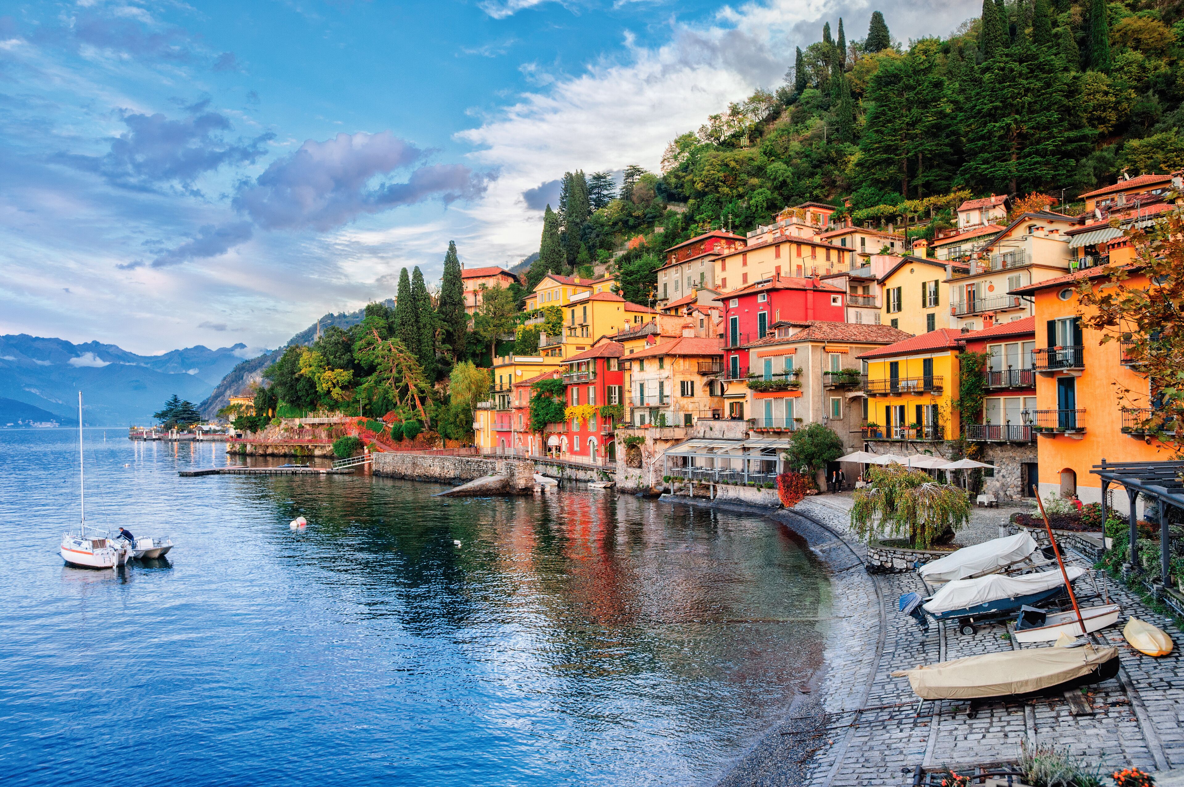 A picturesque lakeside village with colorful buildings, boats, and a calm waterway.