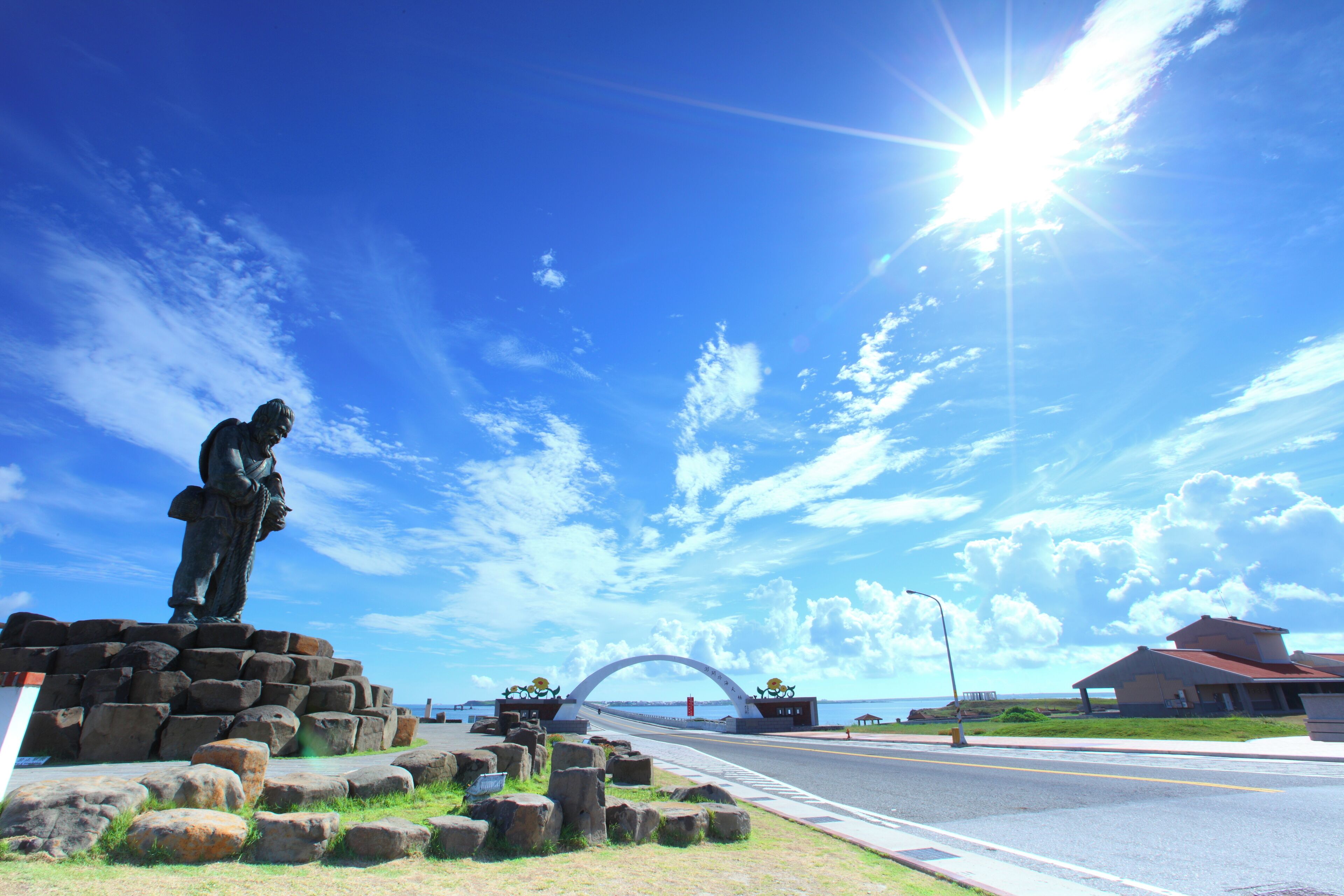 A statue, a bridge, and a building by the water.