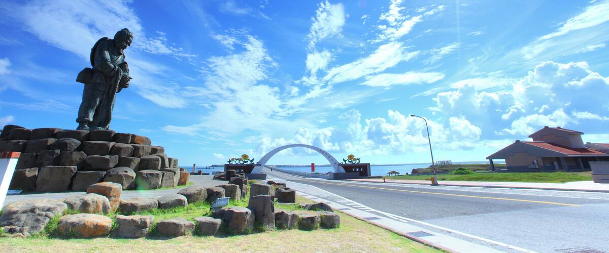A statue, a bridge, and a building by the water.