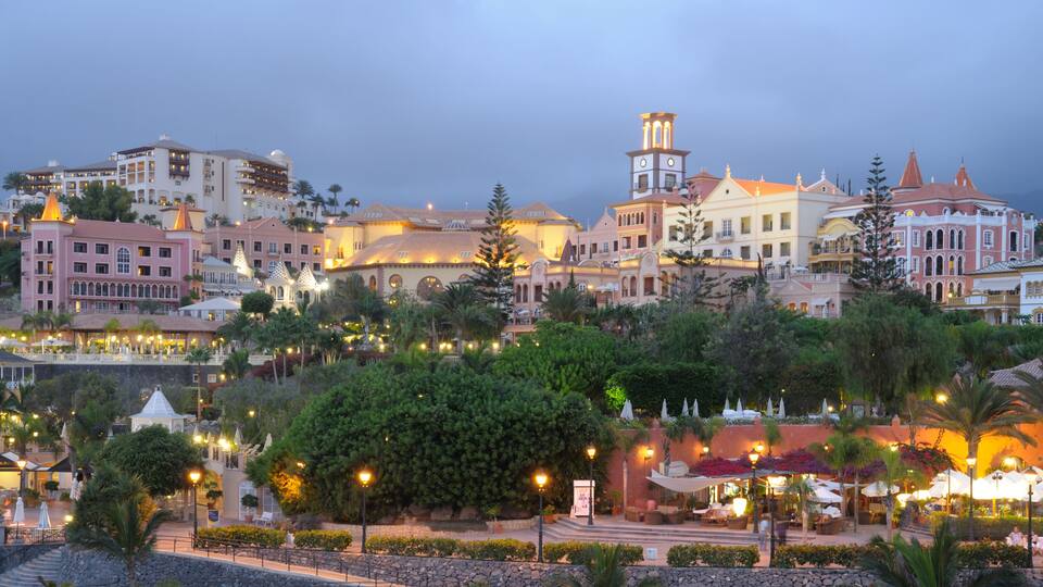 A coastal town with historic buildings, a prominent clock tower, and a well-lit promenade.