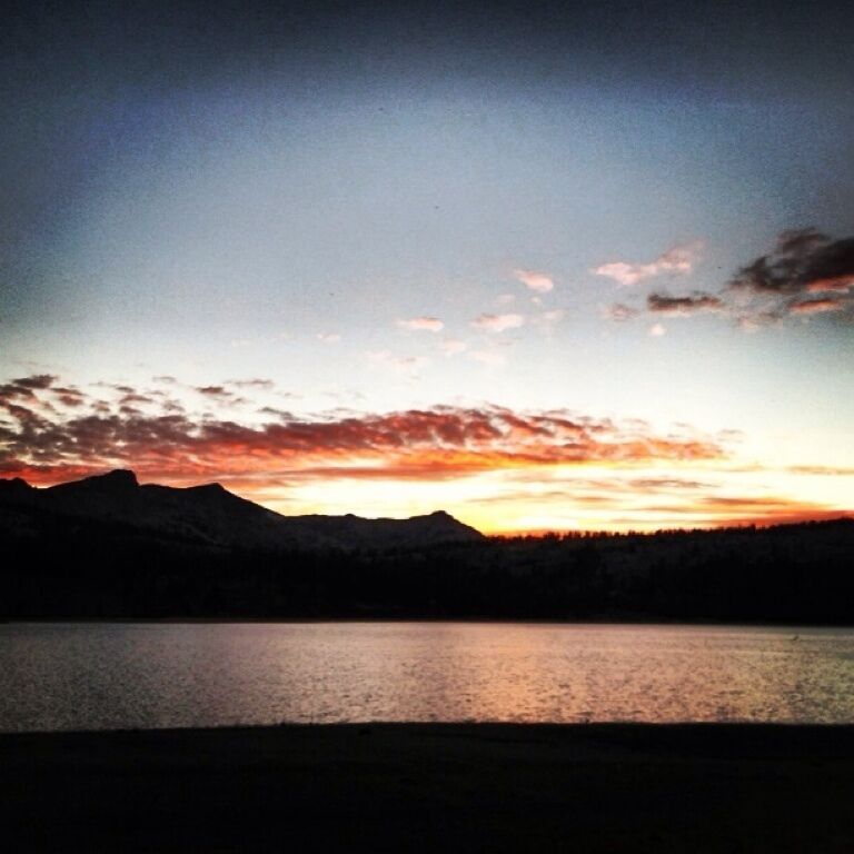 A sunset over a lake with mountains in the background.