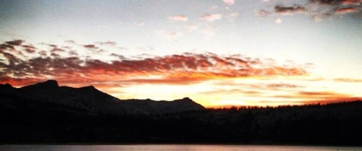 A sunset over a lake with mountains in the background.