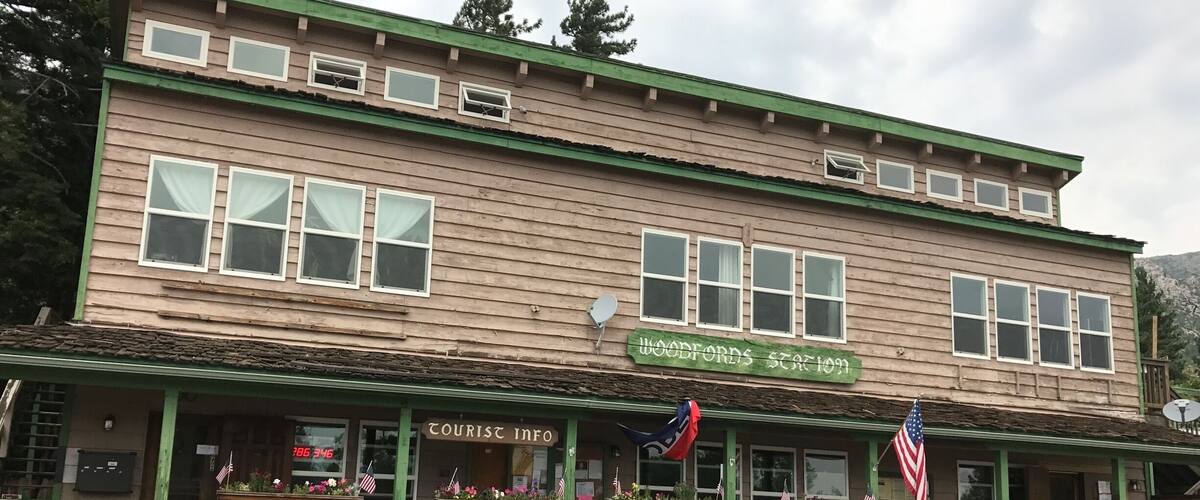 A two-story building with a green facade and a sign reading "Woodford's Station."
