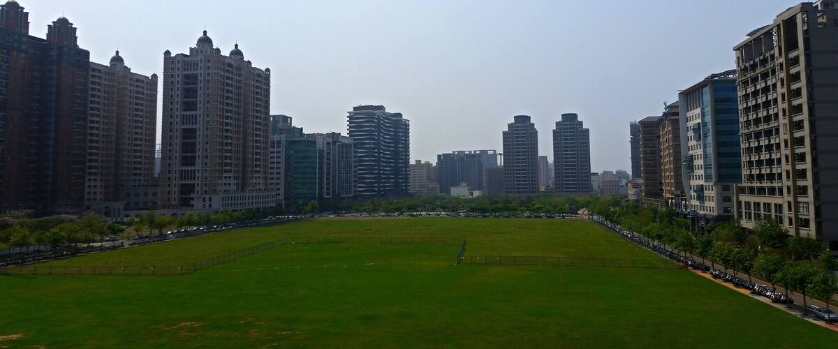 A cityscape with a large green park in the foreground and tall buildings in the background.
