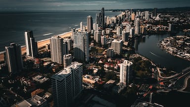 Paisagem costeira com edifícios altos, uma praia e um rio.