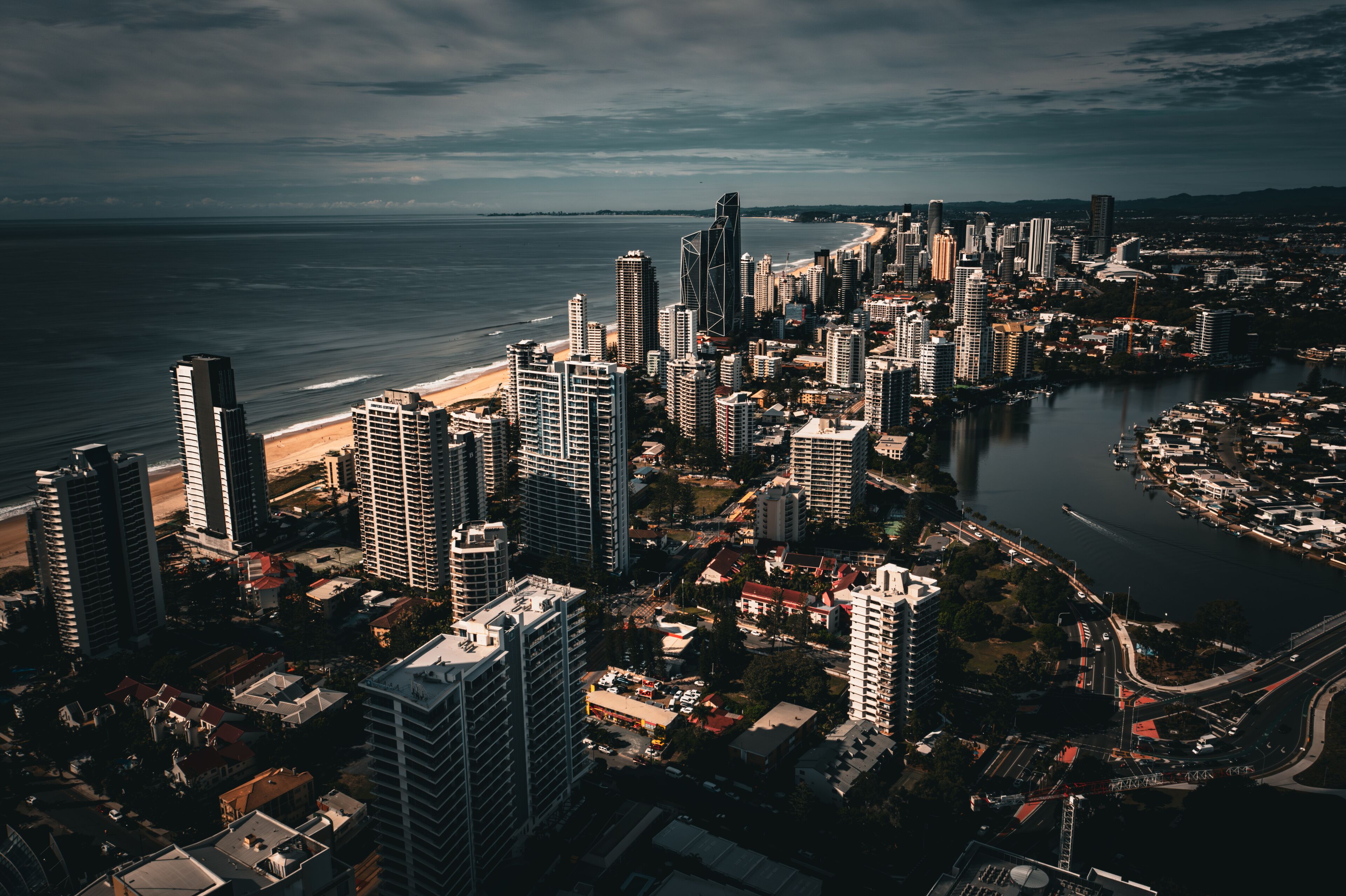 A coastal cityscape with high-rise buildings, a beach, and a river.