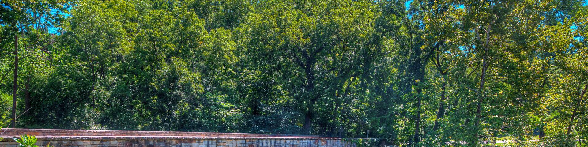 A stone bridge over a clear river surrounded by lush greenery.