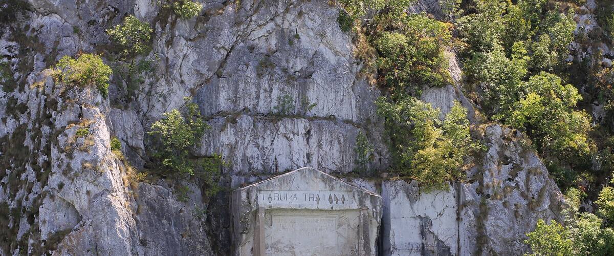 A rocky cliff with a weathered inscription and lush greenery.
