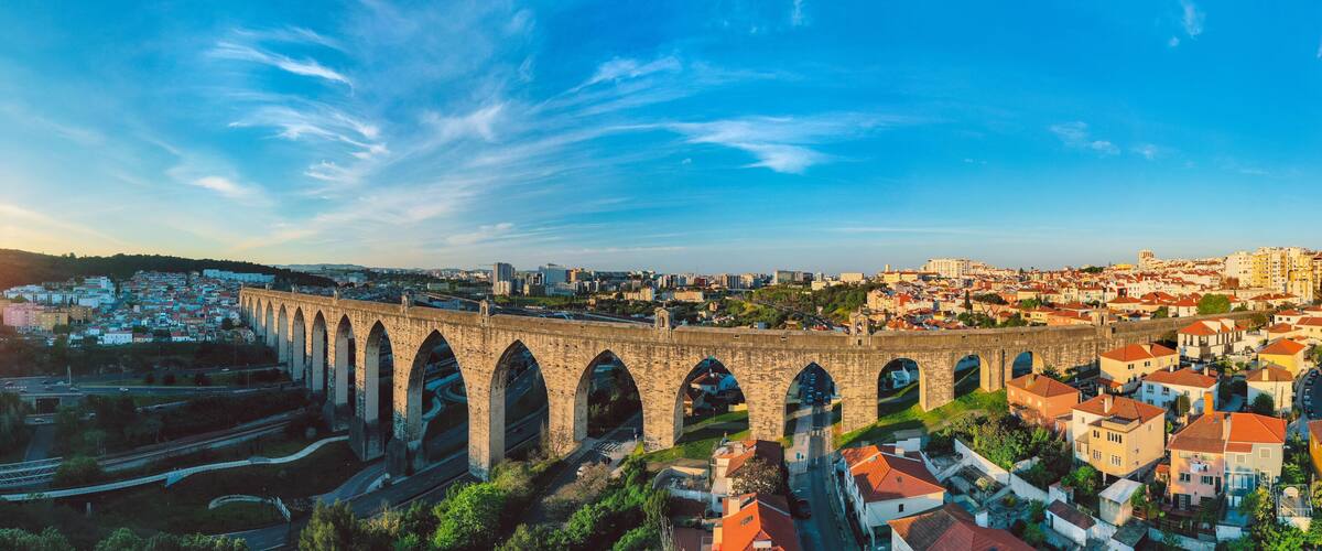 Historic aqueduct in Lisbon city. Aerial panoramic view of The Aguas Livres Aqueduct at sunset. Aqueduto das Aguas Livres or Aqueduct of the Free Waters in Portugal.