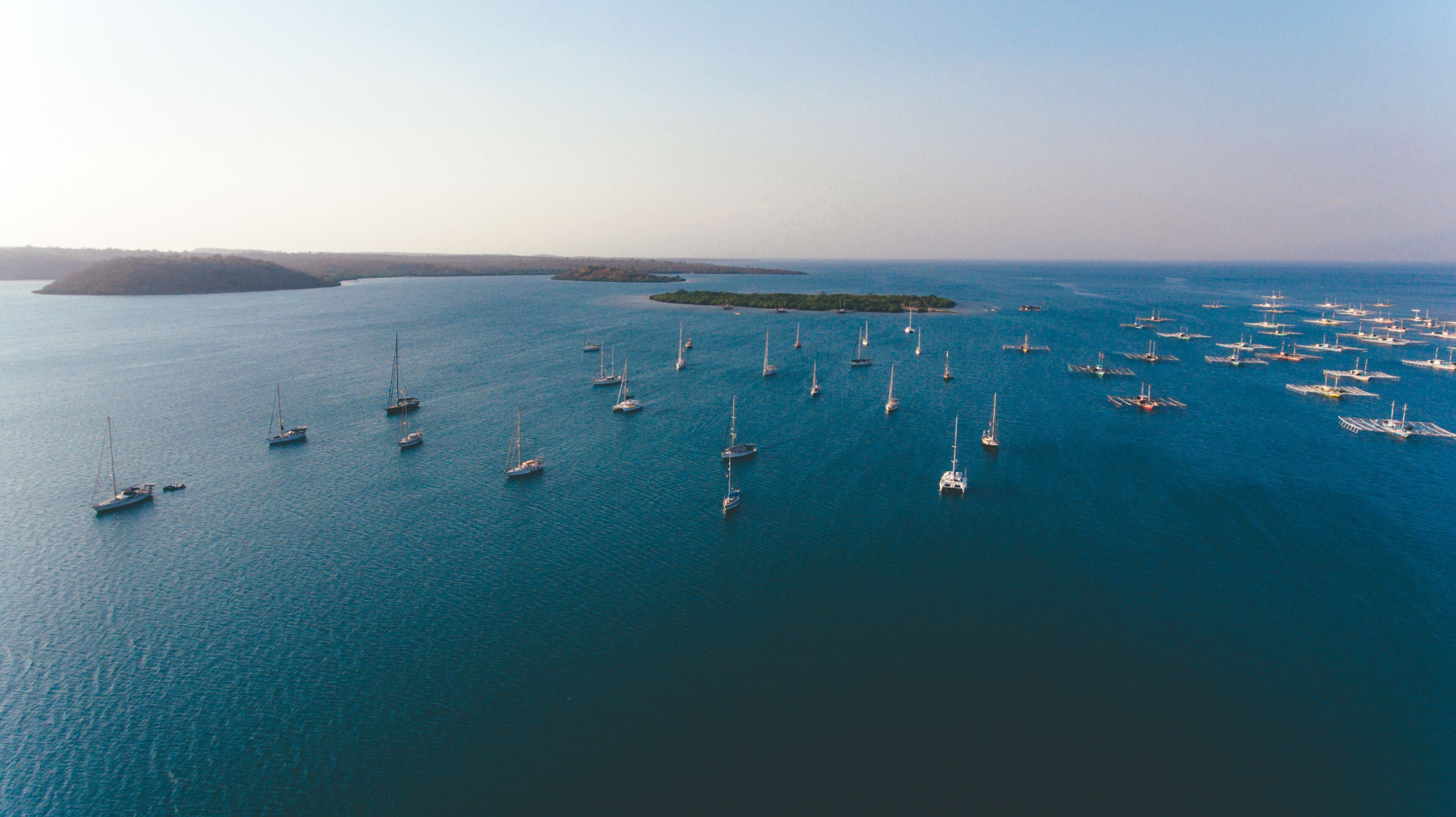 A large body of water with numerous sailboats anchored in the distance.