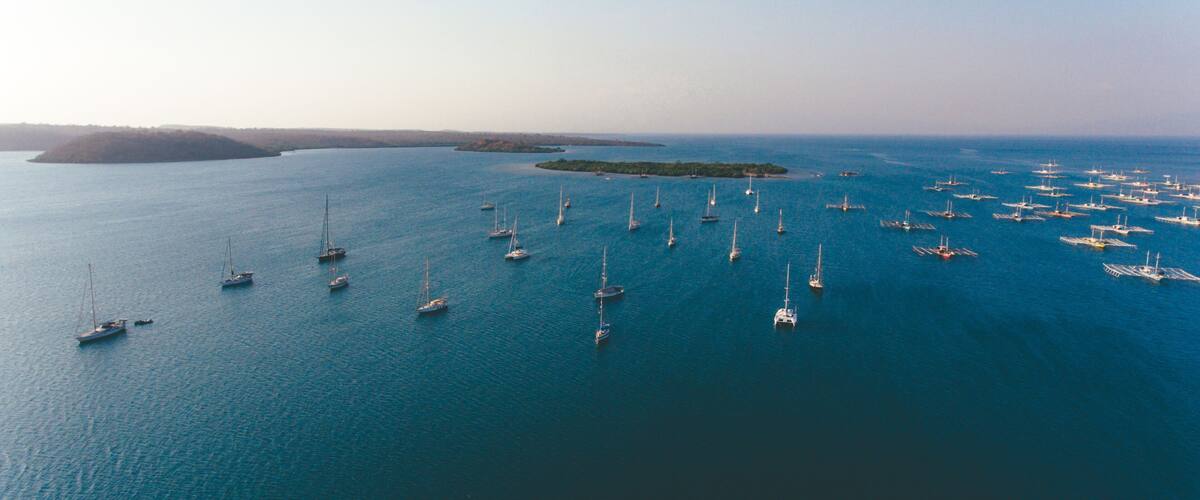 A large body of water with numerous sailboats anchored in the distance.