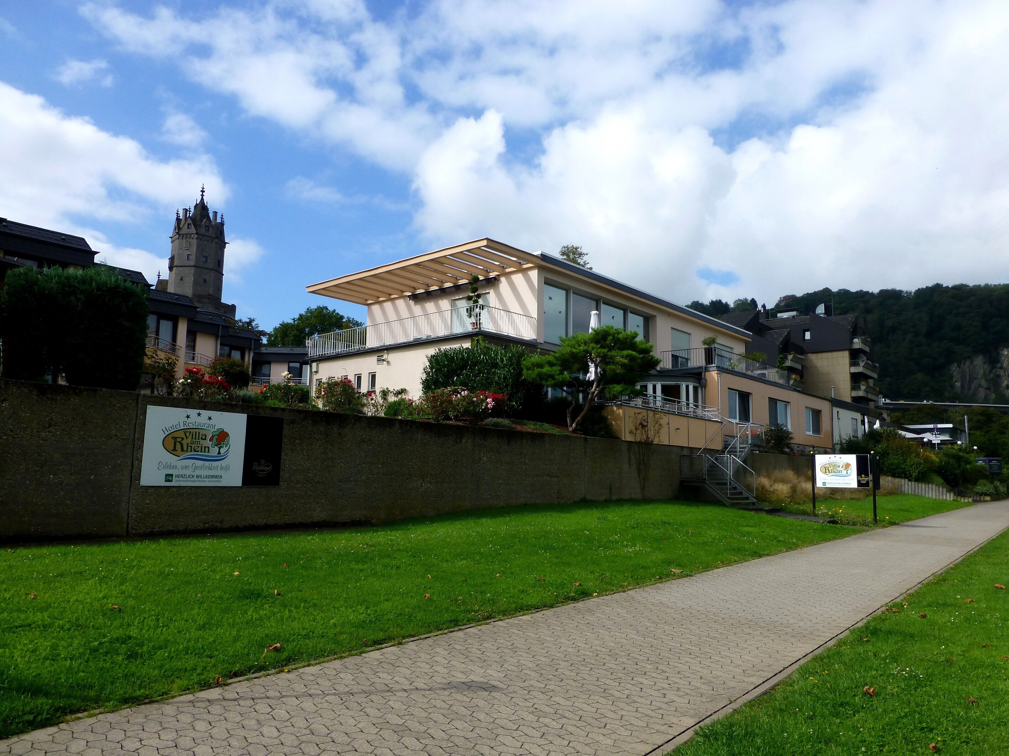 Restaurante de hotel Villa Rülein, con pared de piedra y vegetación al frente.
