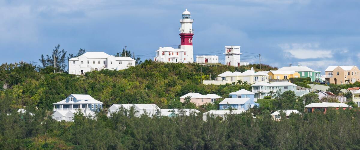 A coastal town with a prominent lighthouse, colorful houses, and lush greenery.