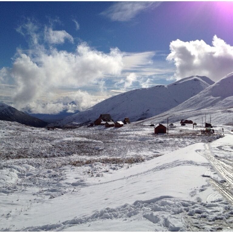 A snowy mountain landscape with several small cabins and a clear sky.