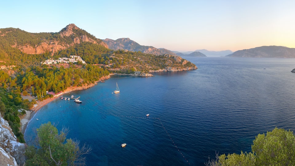 A coastal landscape with a bay, boats, and a small settlement on a hillside.