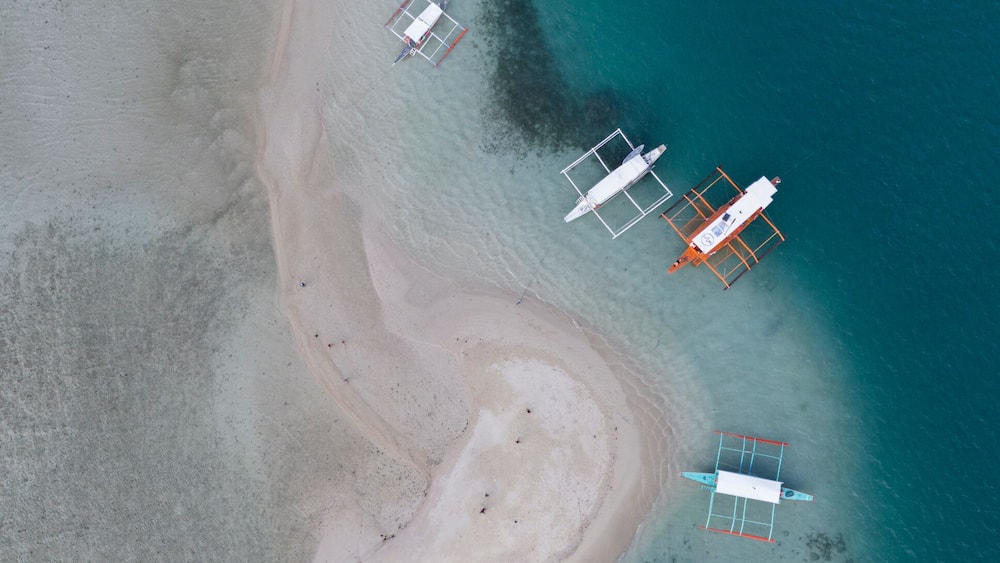 Ein Luftbild eines Strandes mit mehreren Booten, die in der Nähe des Ufers vor Anker liegen.