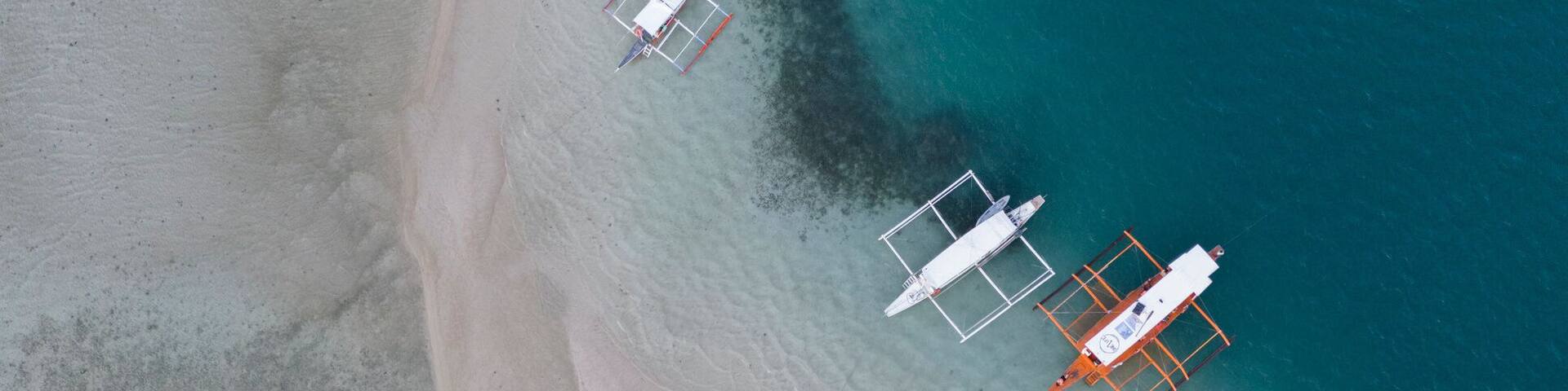 An aerial view of a beach with several boats anchored near the shore.