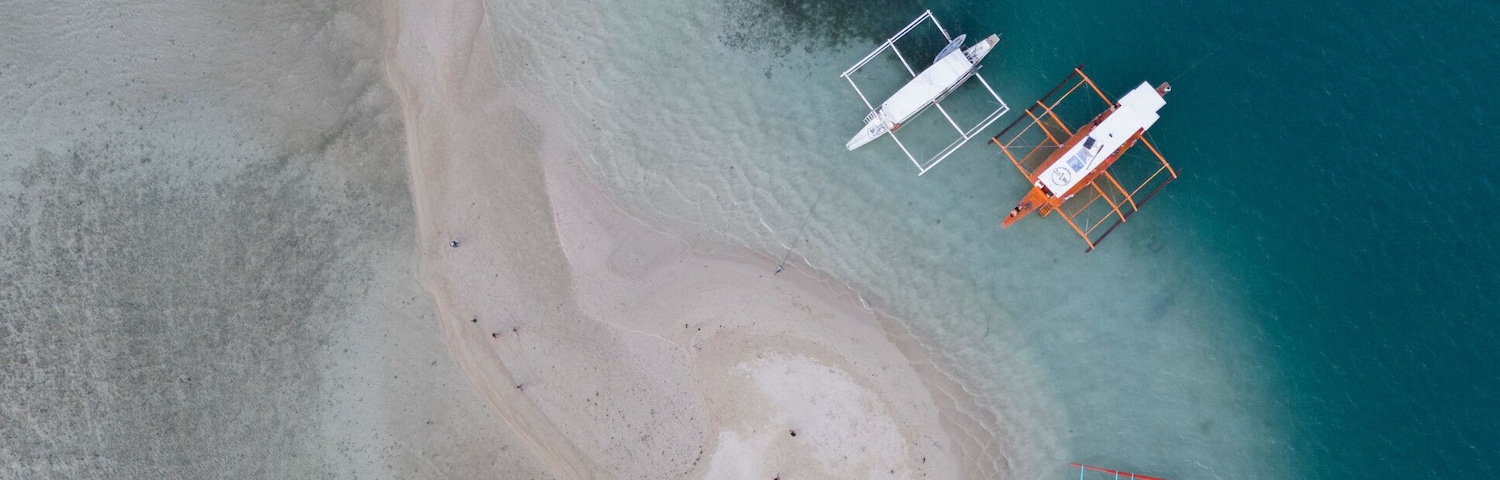 Ein Luftbild eines Strandes mit mehreren Booten, die in der Nähe des Ufers vor Anker liegen.