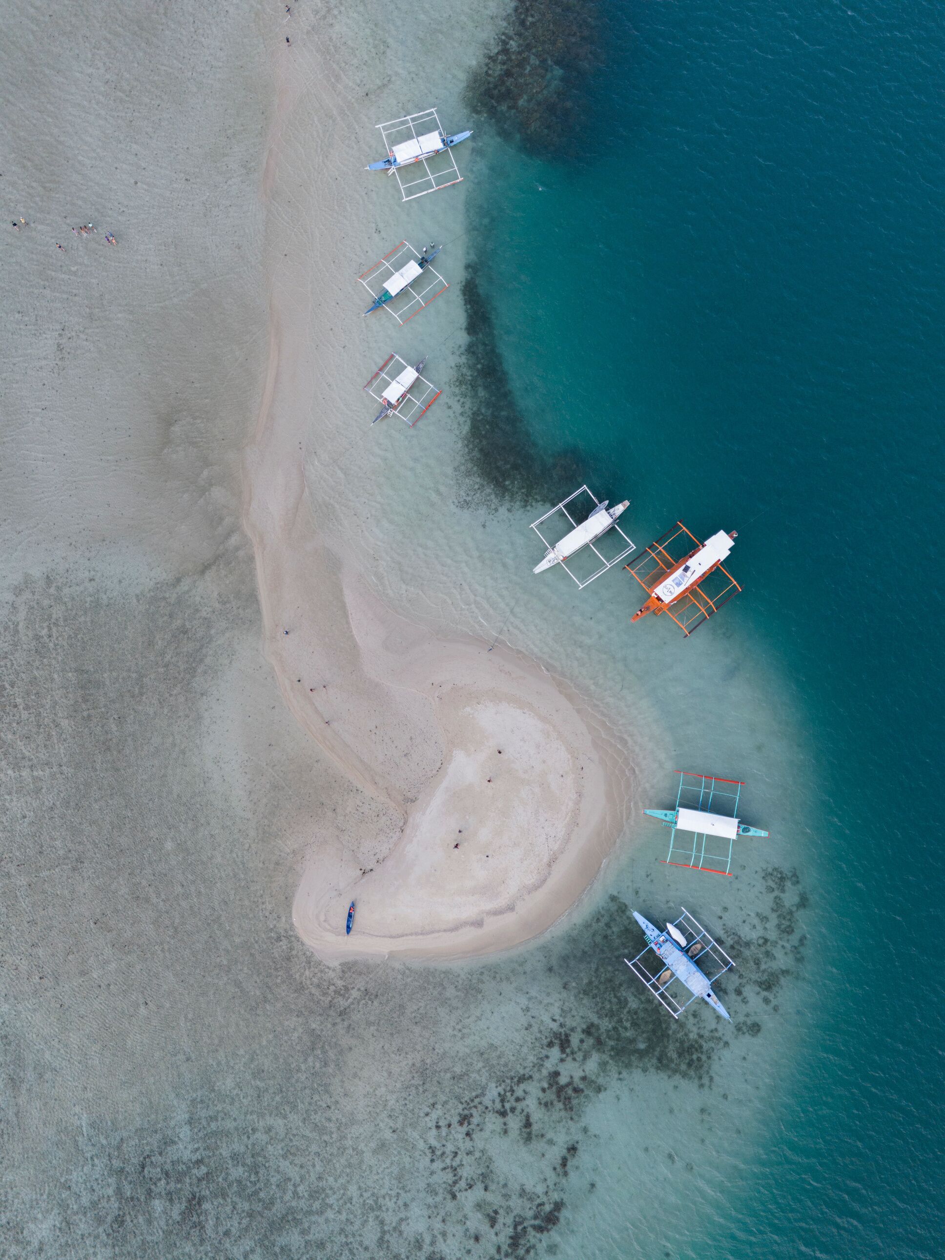An aerial view of a beach with several boats anchored near the shore.