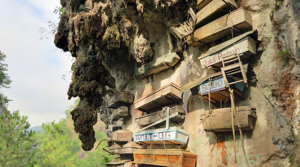 A cliff with wooden structures attached to it, including a sign that reads 'Laka Y Padasan'.