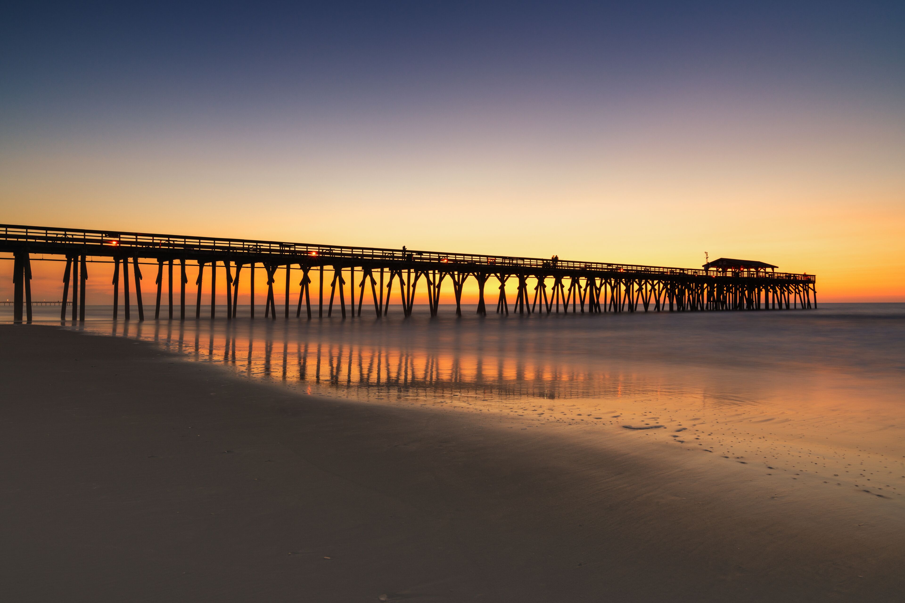 A pier extending into calm waters at sunset.