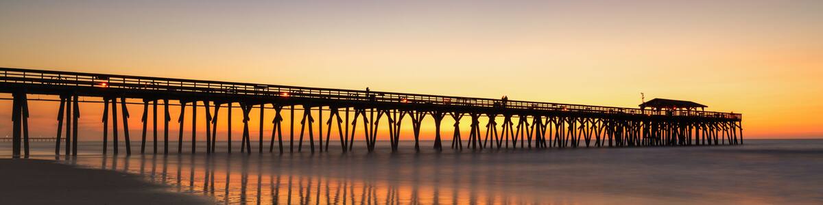Eine Pier, die sich in ruhiges Wasser bei Sonnenuntergang erstreckt.