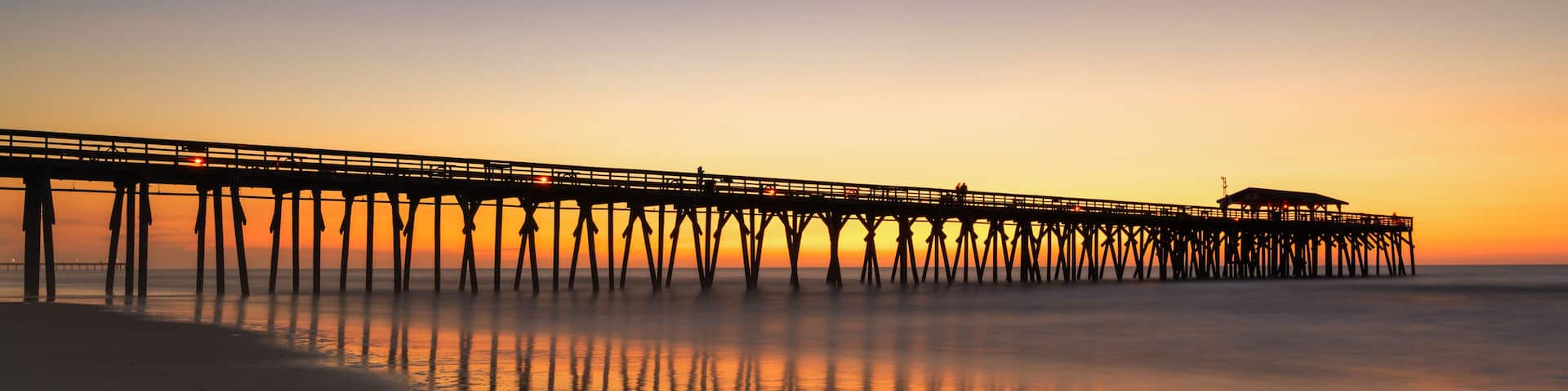 A pier extending into calm waters at sunset.