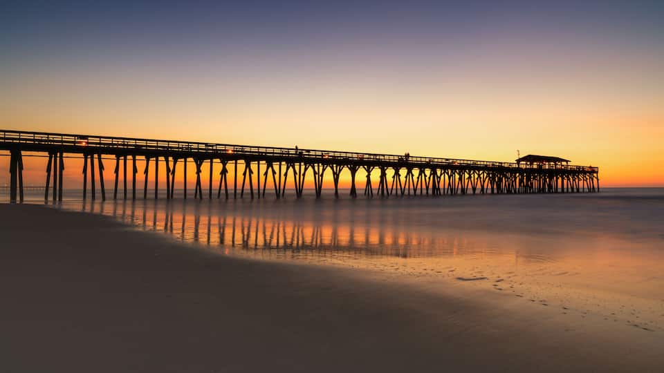 A pier extending into calm waters at sunset.